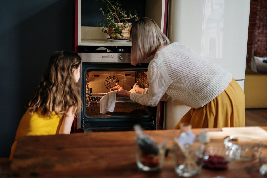 Women putting gluten-free baked goods back into the oven to bake longer