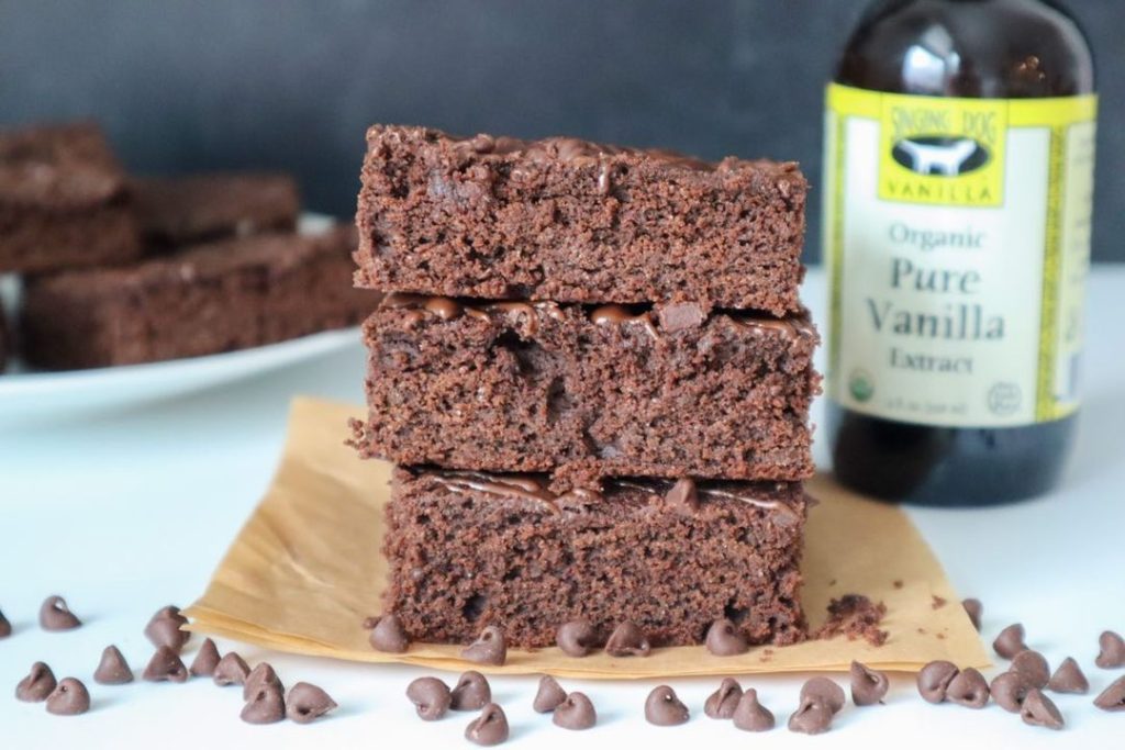 Stack of Paleo Brownies next to a bottle of Singing Dog Vanilla