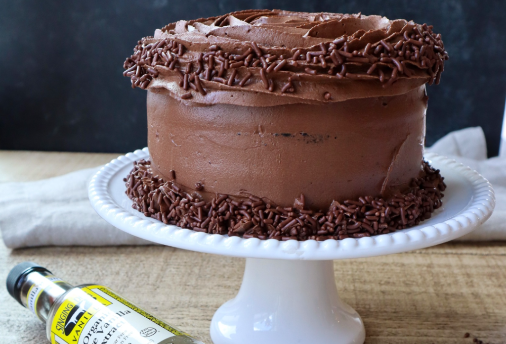 Chocolate Cake on a plate with a bottle of Singing Dog Vanilla